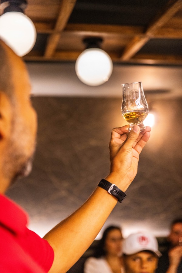 Guía de cata alzando copa Glencairn durante cata mensual en La Boutique del Whisky