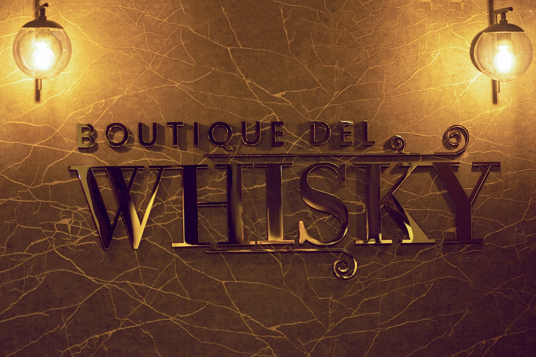 Letrero dorado de Boutique del Whisky sobre el muro de mármol